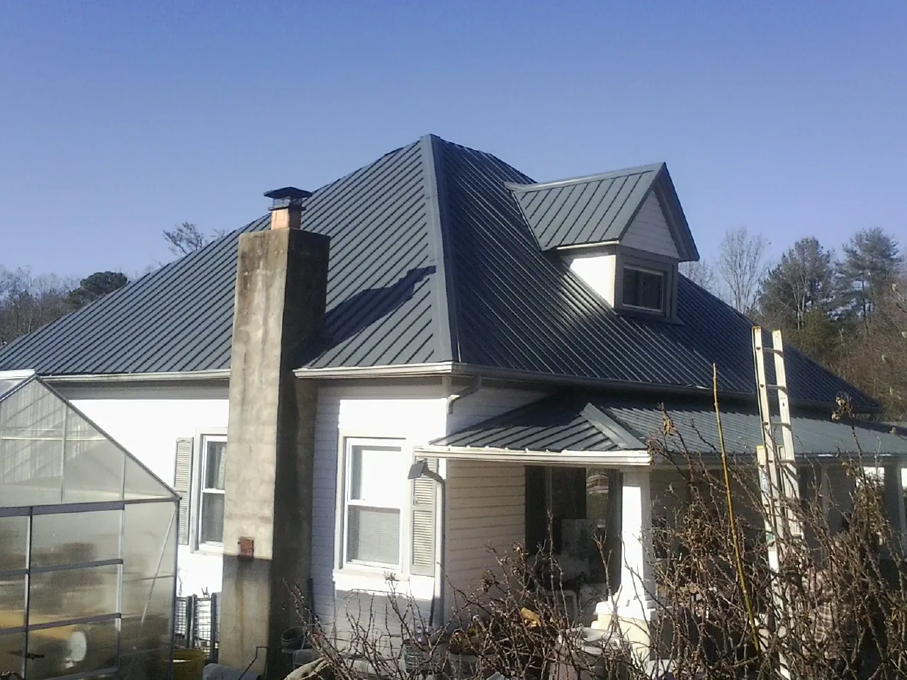 Dark blue standing seam metal roof on a white farmhouse with dormer — Slate & Tile Roof Repair by Roofing Brothers in Elma