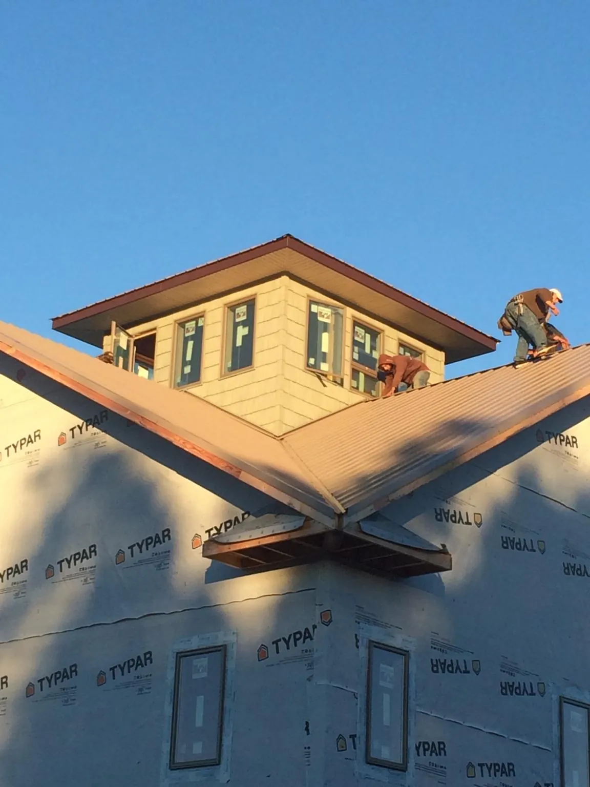 Roofers working around a rooftop cupola on a new metal roof at sunset — Roof Waterproofing in Elma by Roofing Brothers